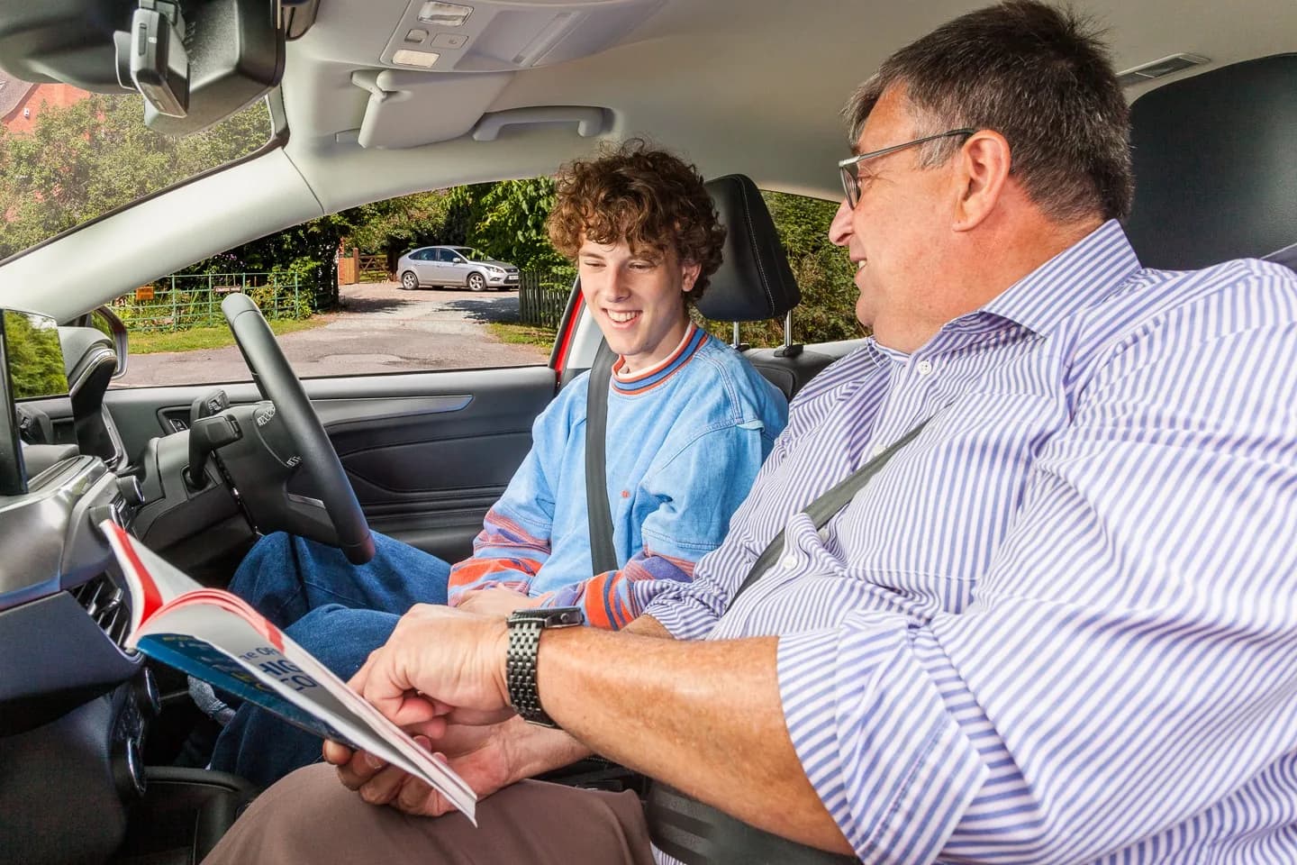 Learner driver and instructor discussing progress inside a parked car