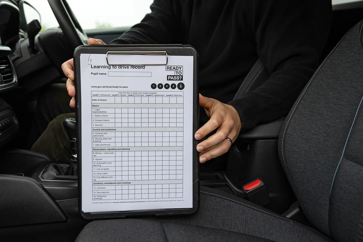 Official learning-to-drive record held on a clipboard inside a car