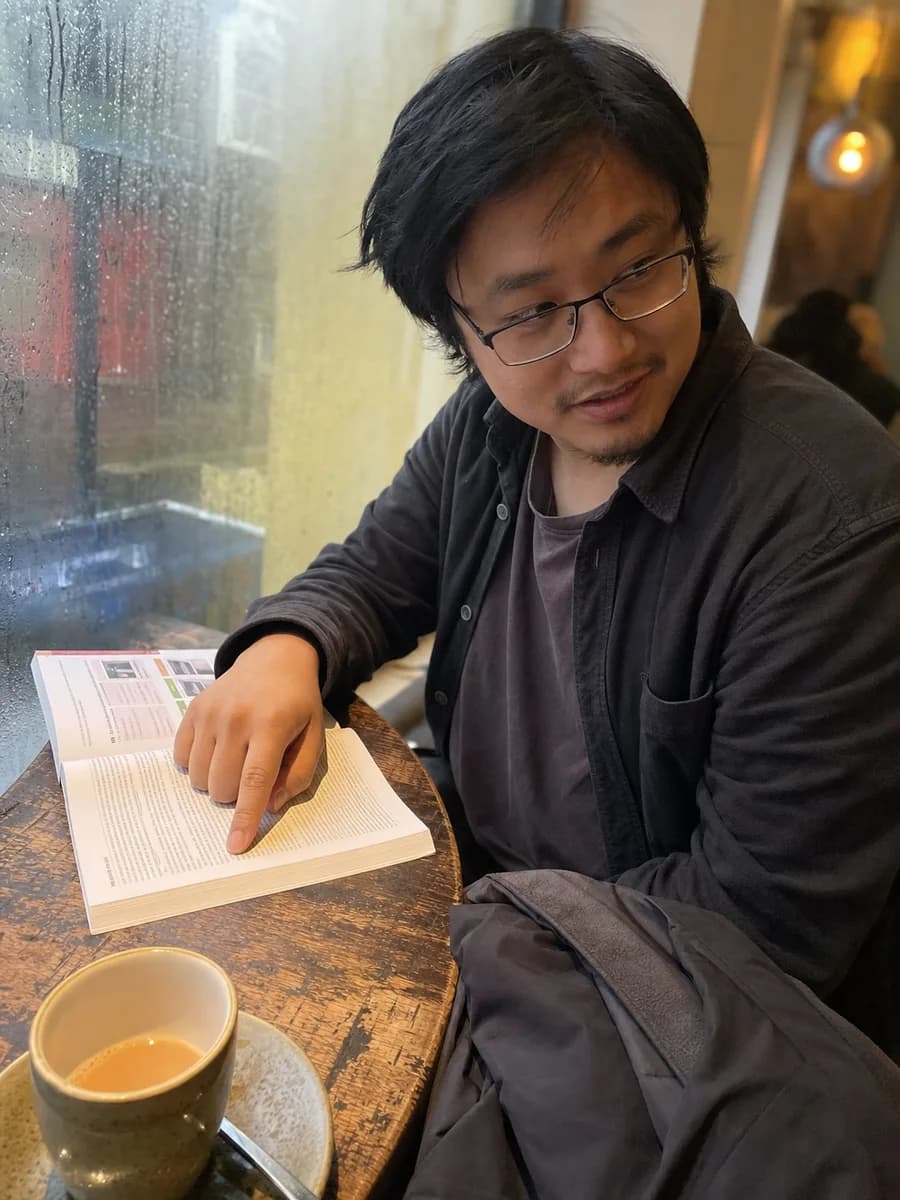 Illustrative learner reading a road-rules handbook in a cafe