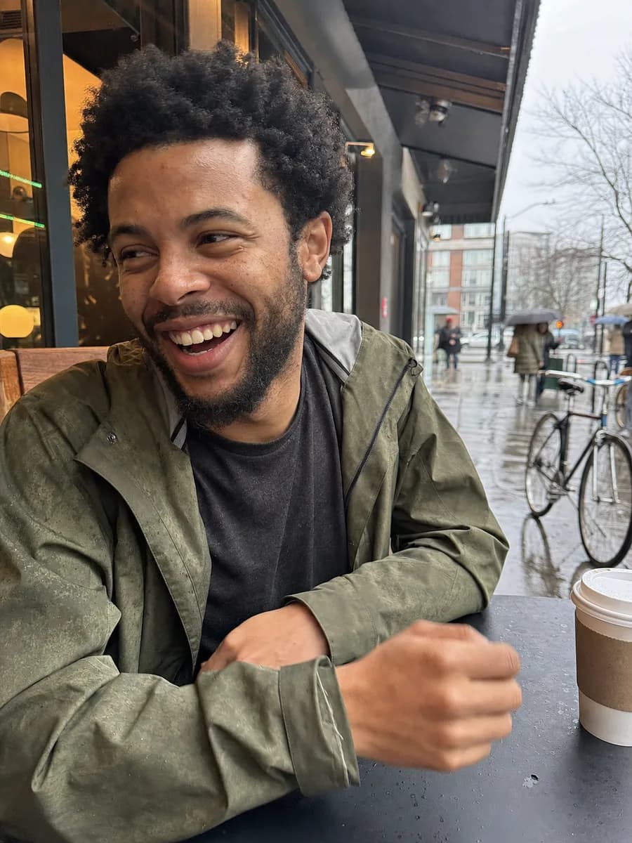 Illustrative learner laughing at an outdoor cafe on a rainy Seattle afternoon