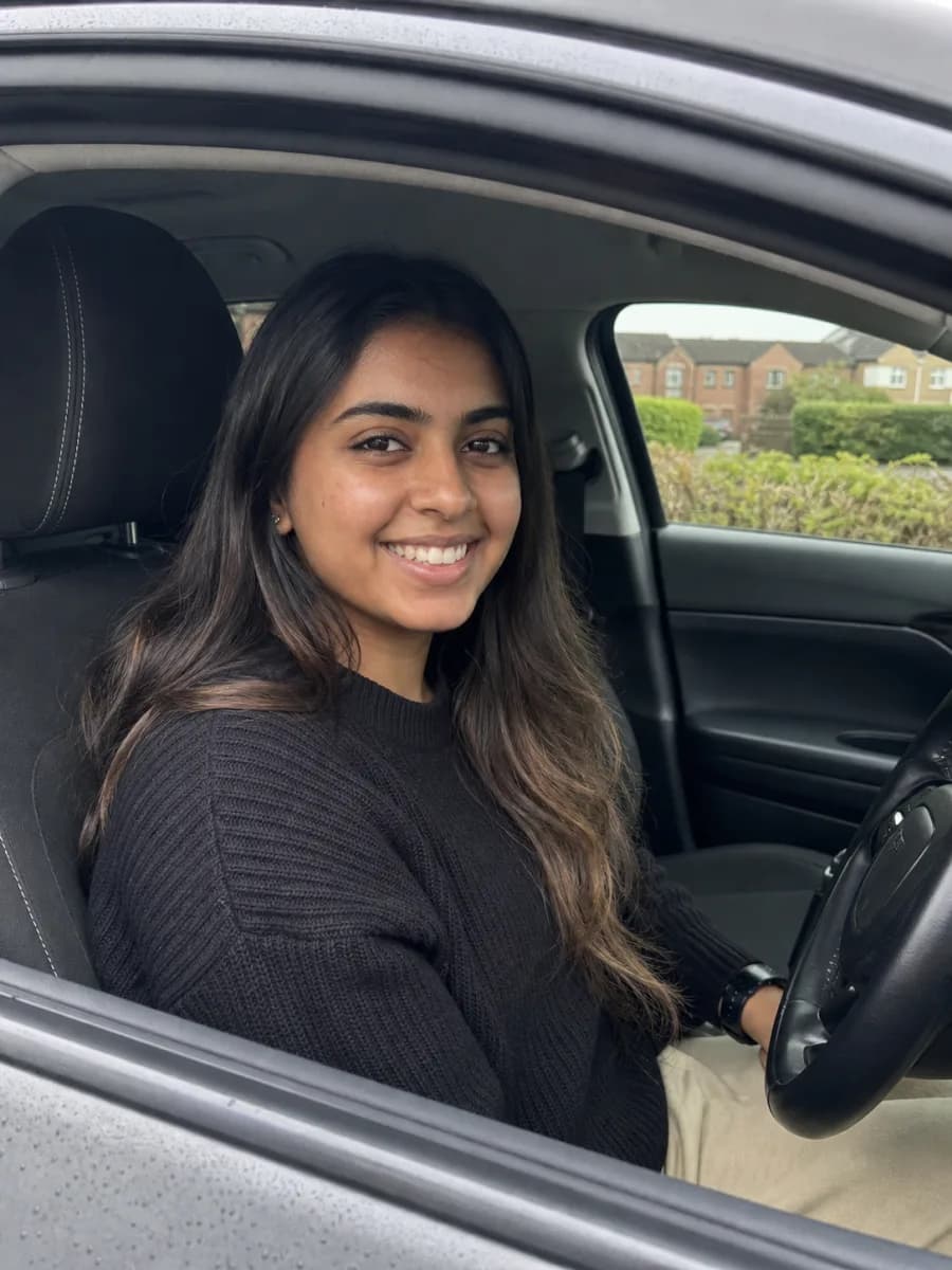 Illustrative learner sitting in the driver seat of a parked car
