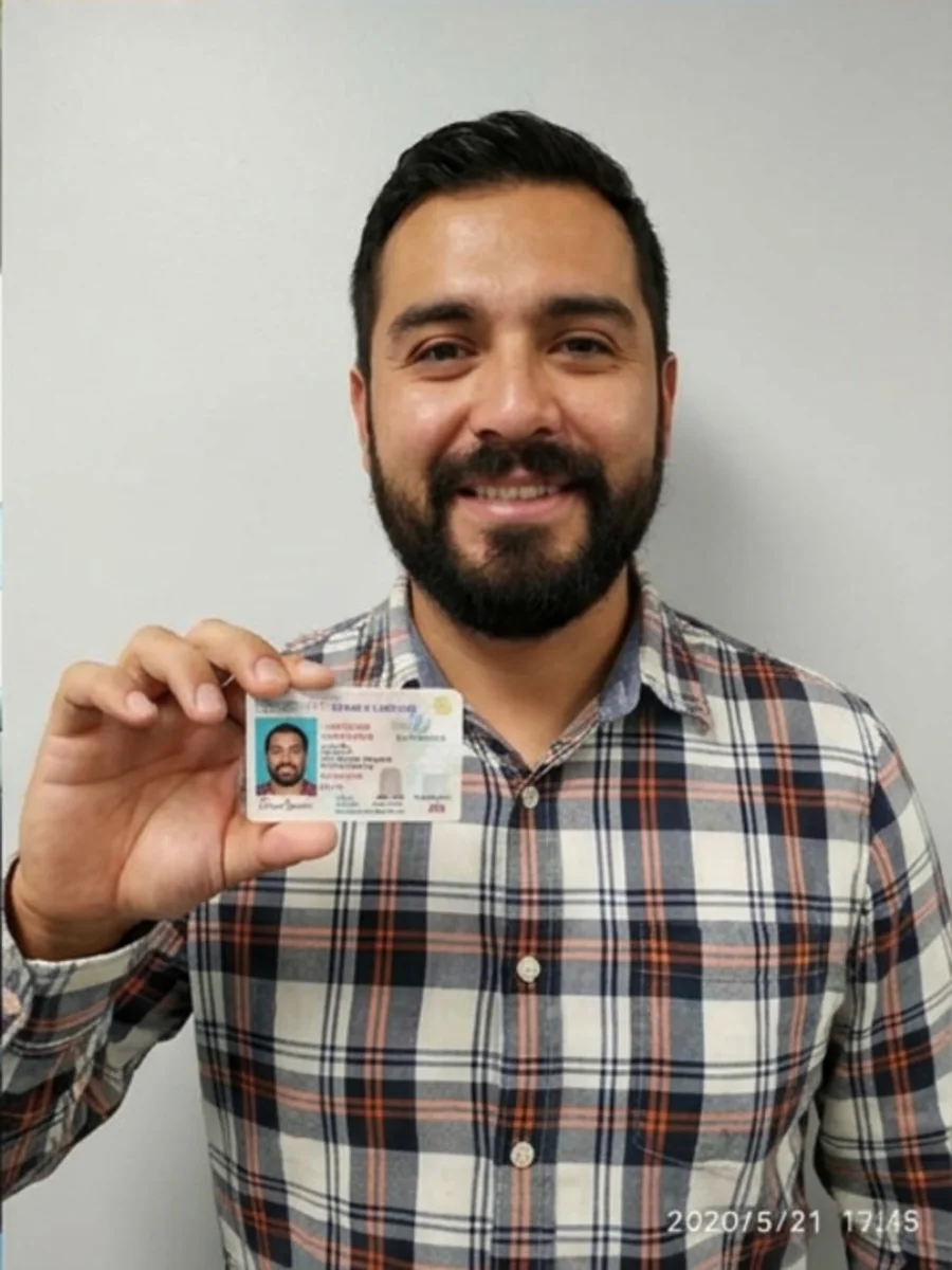 Illustrative learner holding a permit card indoors